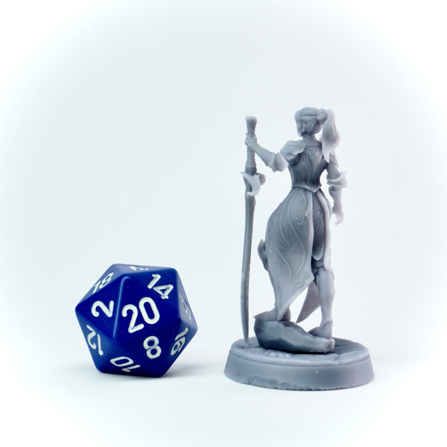 Gray figurine of a warrior with a blue polyhedral dice on a white background