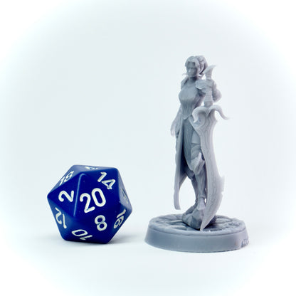 Gray fantasy figurine next to a blue polyhedral dice on a white background
