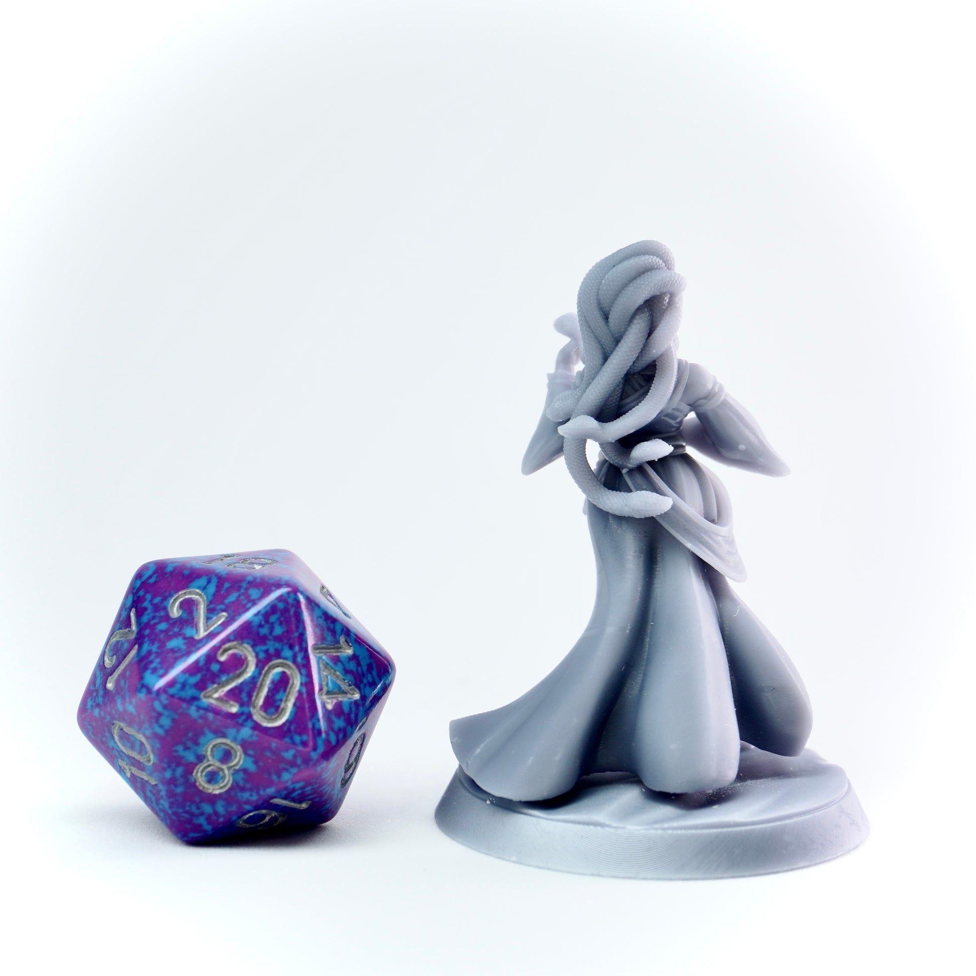 Gray fairy figurine with a purple and blue die on a white background