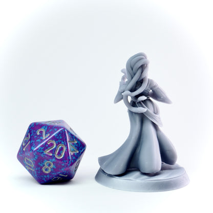Gray fairy figurine with a purple and blue die on a white background