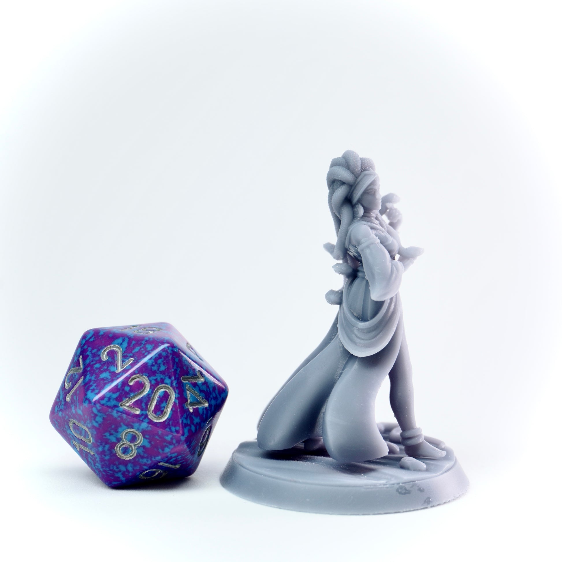 Gray figurine of a fantasy character next to a purple polyhedral dice on a white background