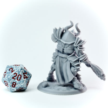 Gray fantasy figurine with armor and a weapon next to a polyhedral dice on a white background