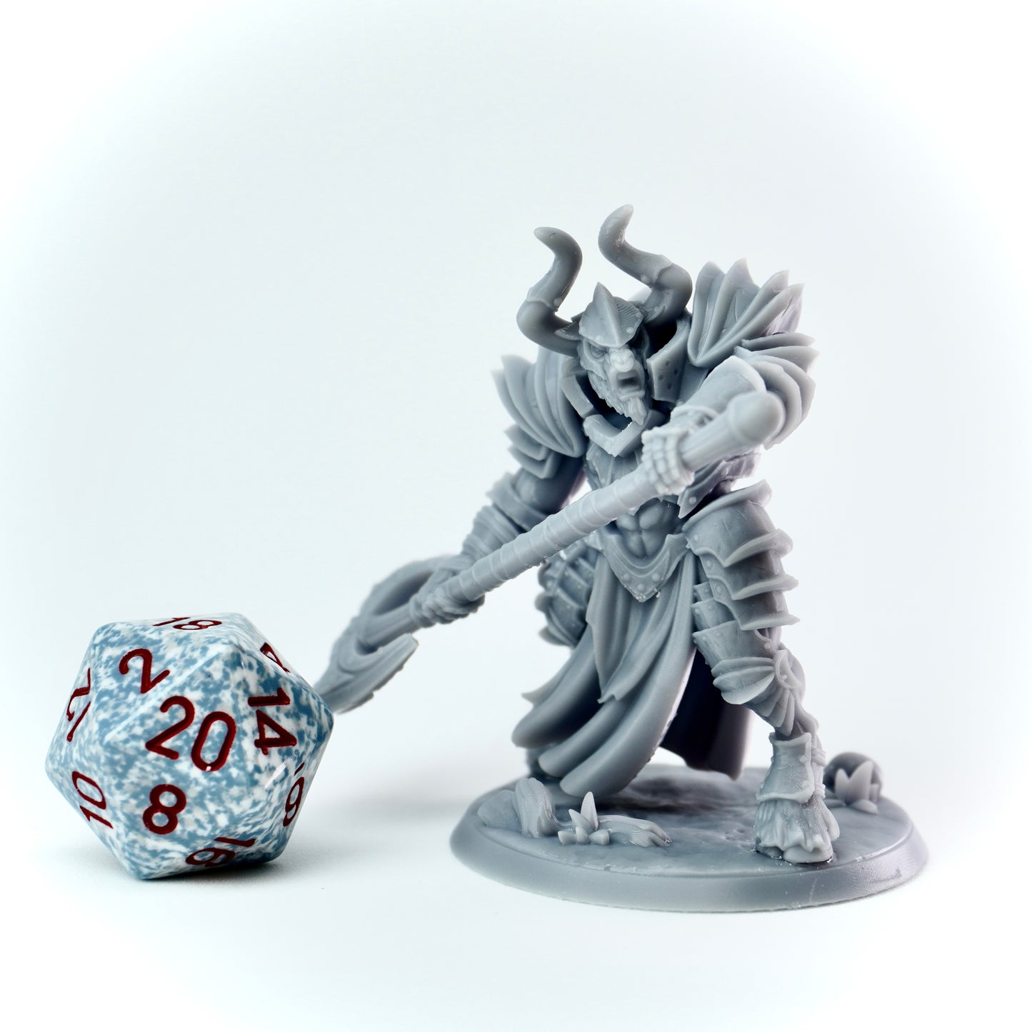Gray fantasy figurine with a large axe and a D20 dice on a white background