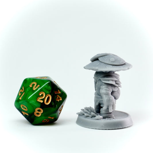 Green polyhedral dice with gold numbers next to a gray miniature figure on a white background