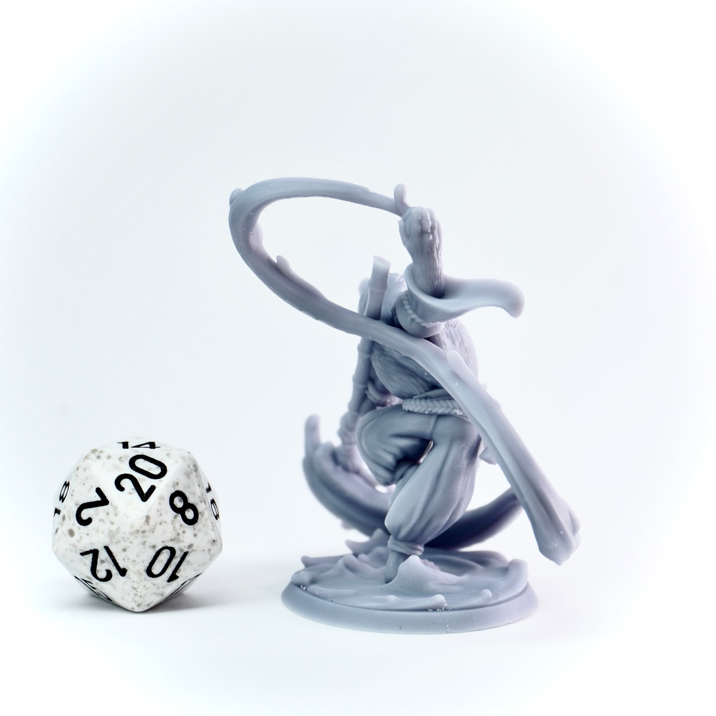 Gray fantasy figurine with a brush next to a polyhedral dice on a white background