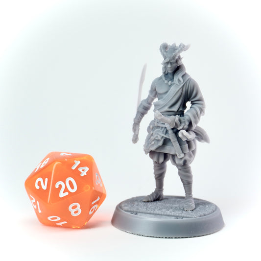 Gray miniature figure of a warrior with a sword next to an orange polyhedral dice on a white background