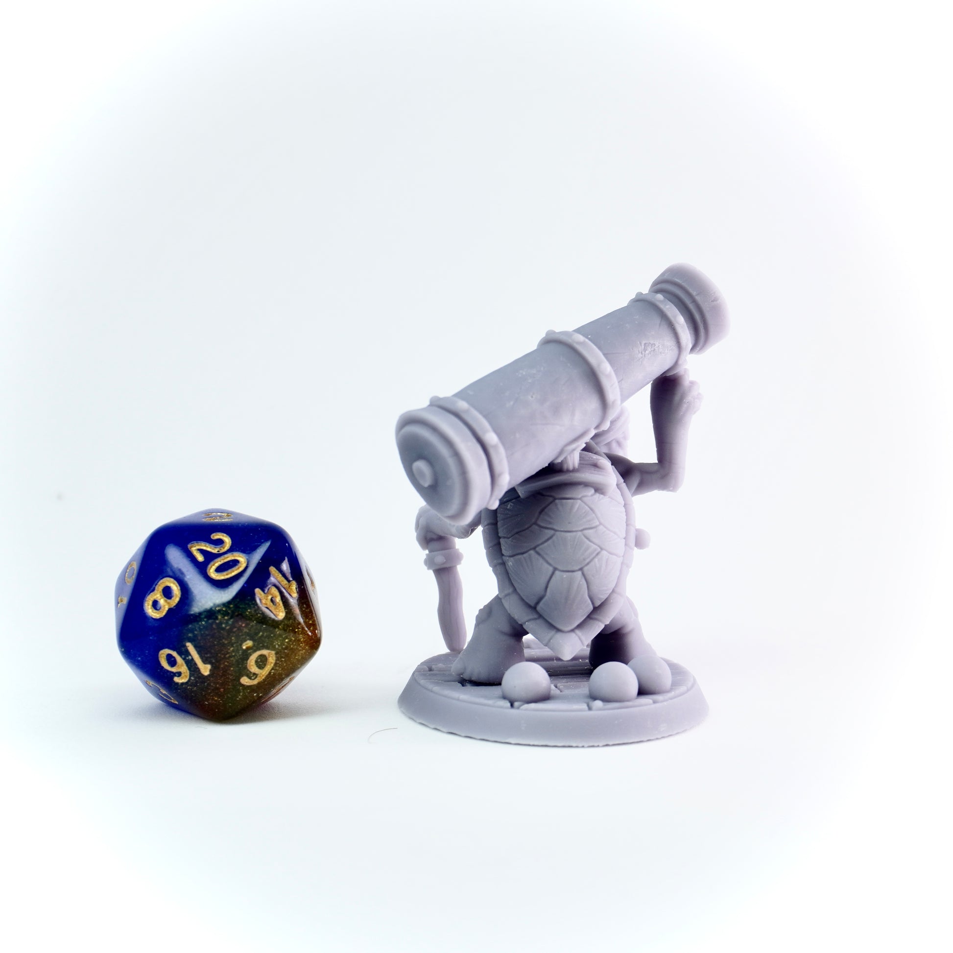 Gray figurine with a cannon and a blue and gold die on a white background