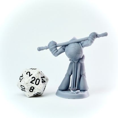 Gray miniature figure with a staff next to a twenty-sided die on a white background