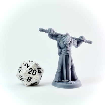 Gray miniature figure with a staff next to a twenty-sided die on a white background