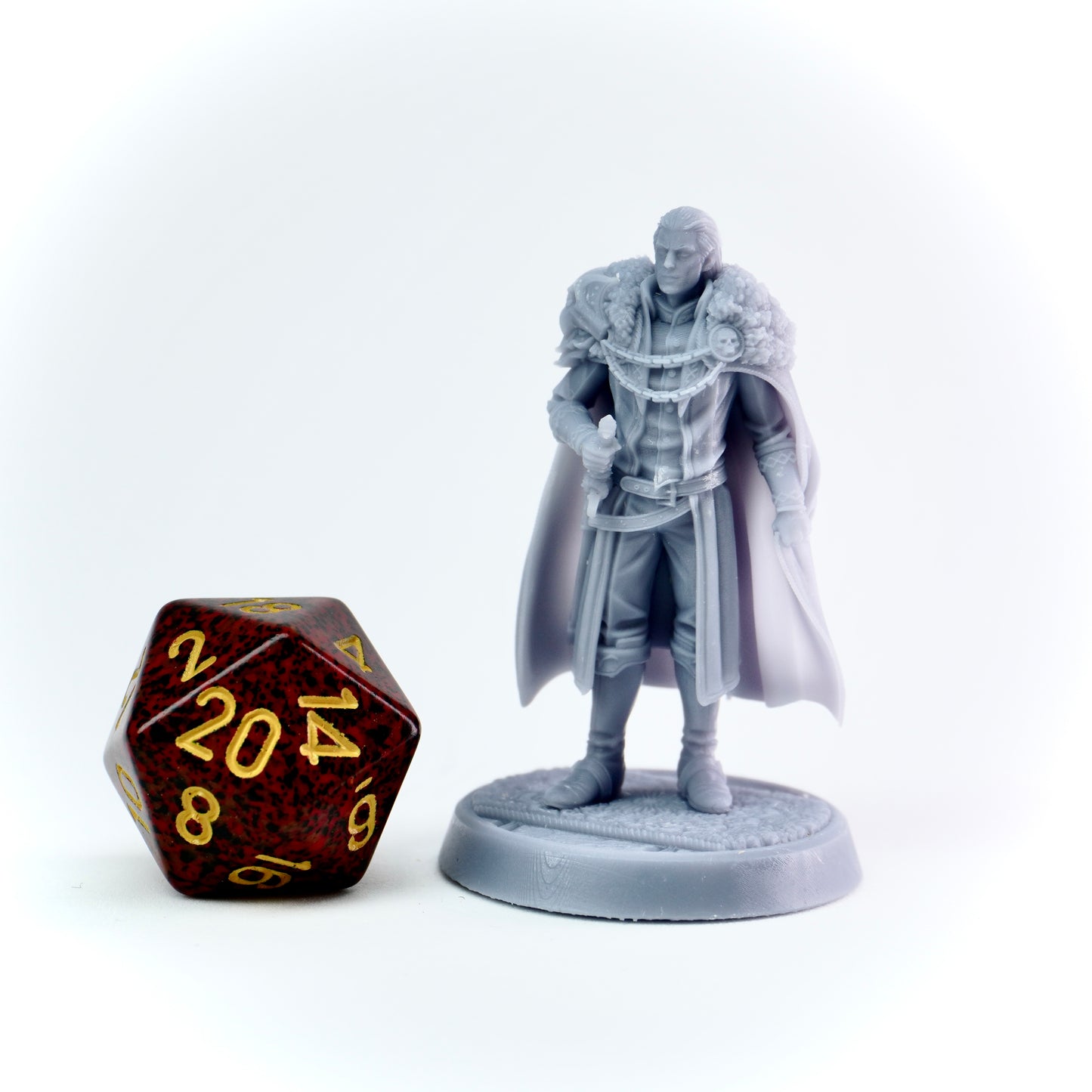 Gray miniature figure of a warrior with a cape next to a brown polyhedral dice on a white background