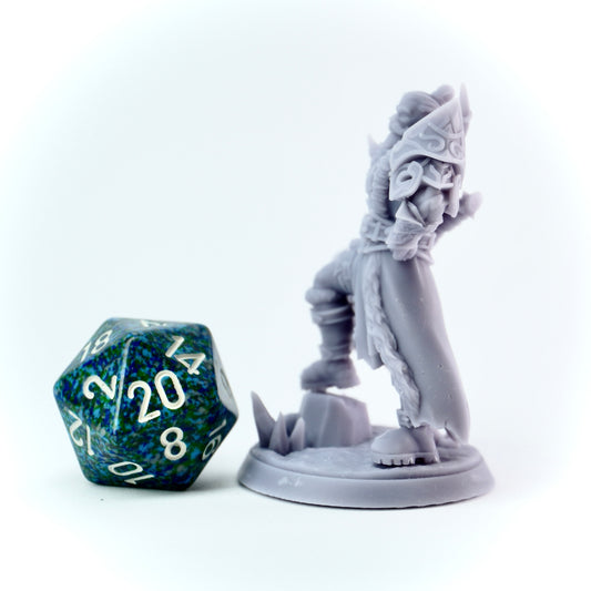 Gray viking-like fantasy figurine next to a green and blue polyhedral dice on a white background