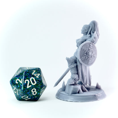 Gray figurine of a warrior with a shield and sword next to a D20 dice on a white background