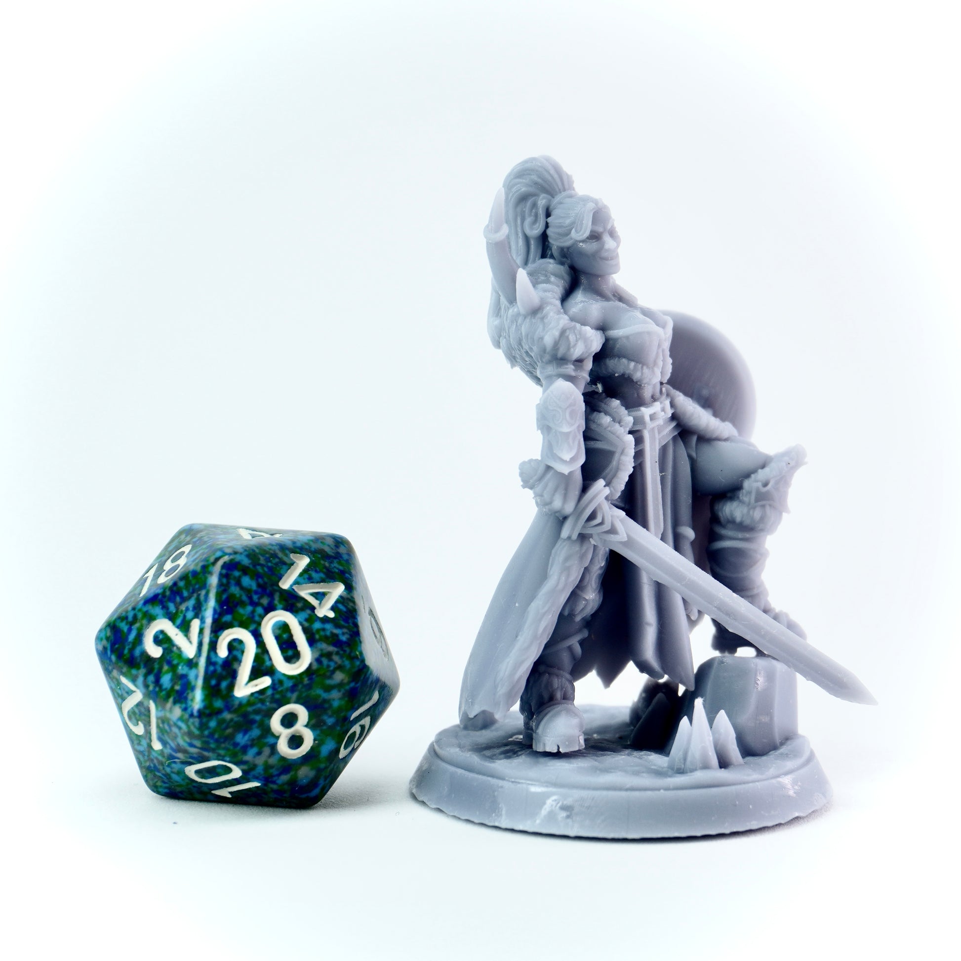Gray fantasy figurine with a sword next to a D20 dice on a white background