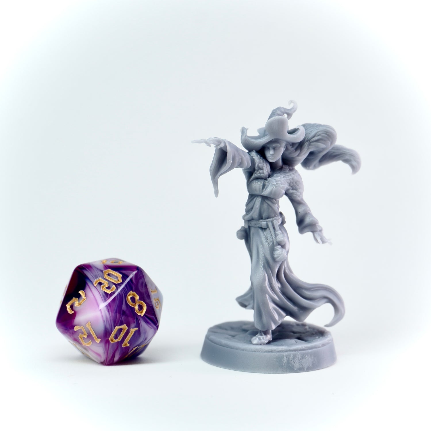 Gray fantasy figurine with a purple and white polyhedral dice on a white background