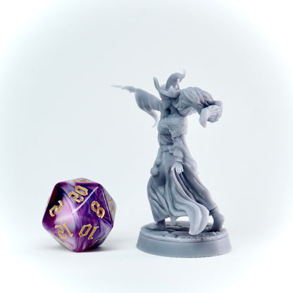 Gray fantasy figurine next to a purple polyhedral dice on a white background