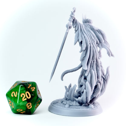 Gray fantasy figurine with a longsword next to a green polyhedral dice on a white background