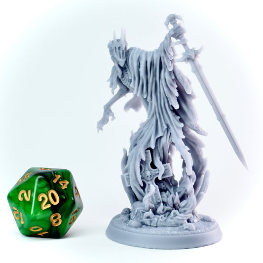 Gray fantasy ghost figurine with a longsword next to a green polyhedral dice on a white background