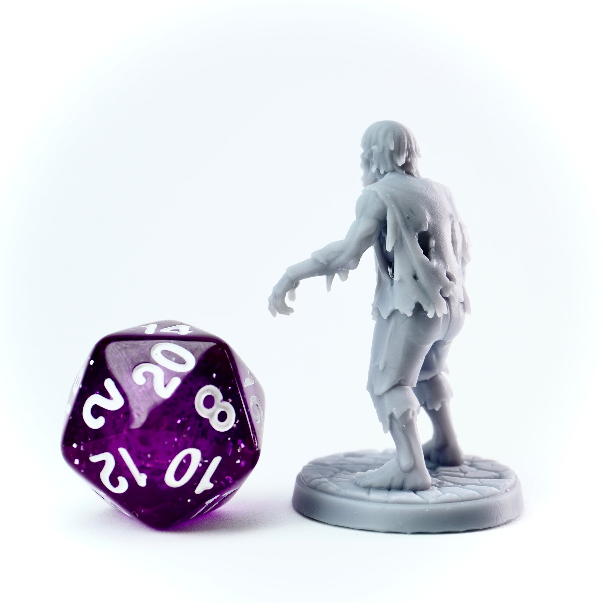 Gray zombie figurine and purple polyhedral dice on a white background