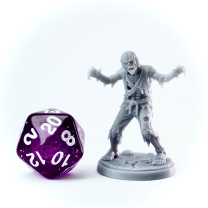 Zombie figurine next to a purple polyhedral dice on a white background