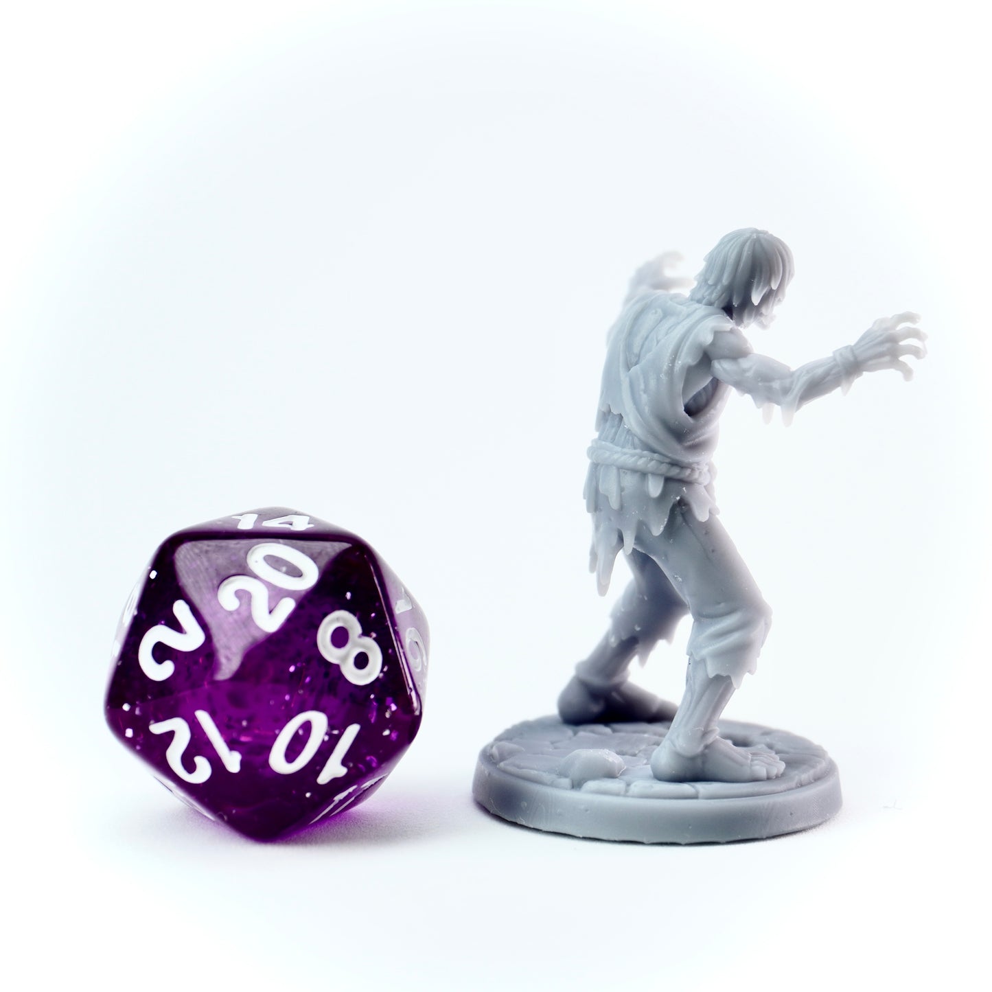 Gray zombie figurine and purple polyhedral dice on a white background