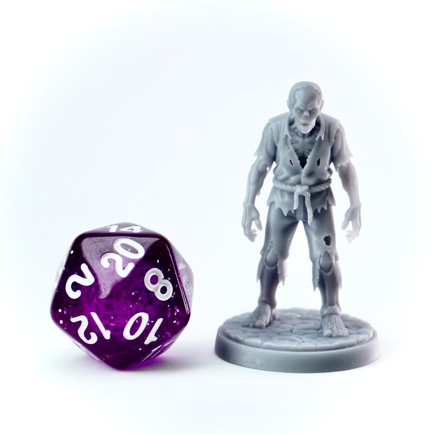 Zombie figurine and purple polyhedral dice on a white background