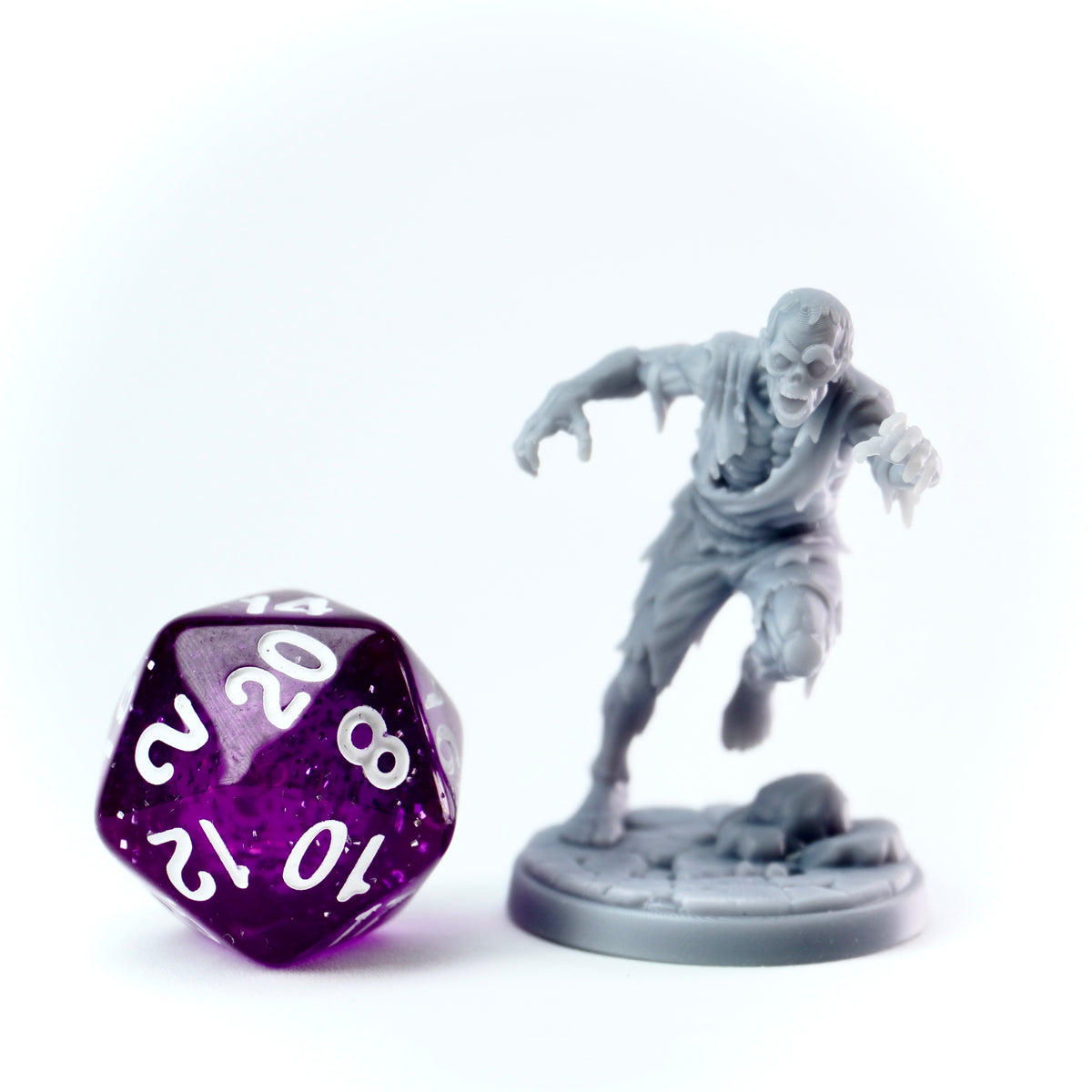 Attacking Zombie figurine and purple dice on a white background