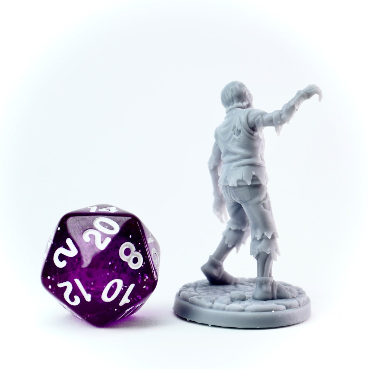 Gray miniature figure of a character character and a purple polyhedral dice on a white background