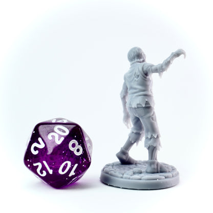 Gray miniature figure of a character character and a purple polyhedral dice on a white background