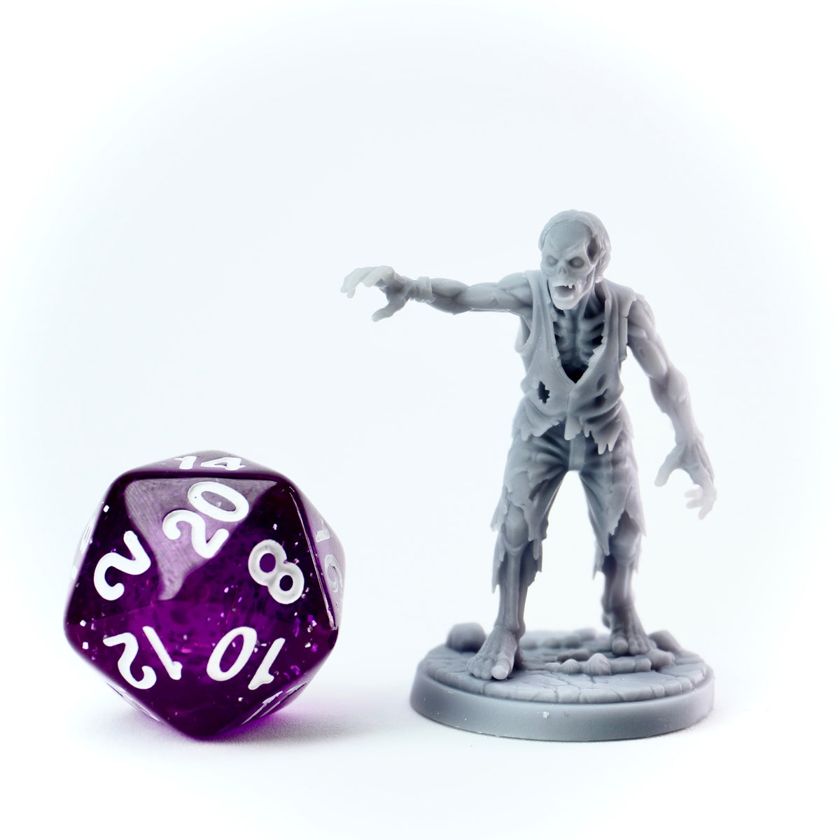 Zombie figurine next to a purple twenty-sided die on a white background