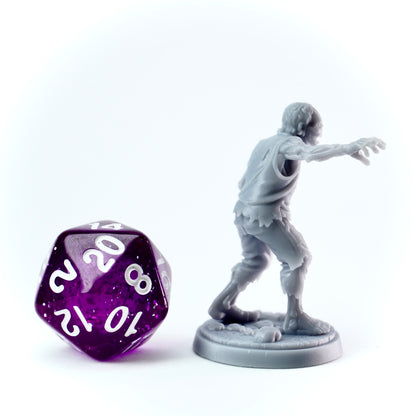 Gray zombie figurine next to a purple twenty-sided die on a white background