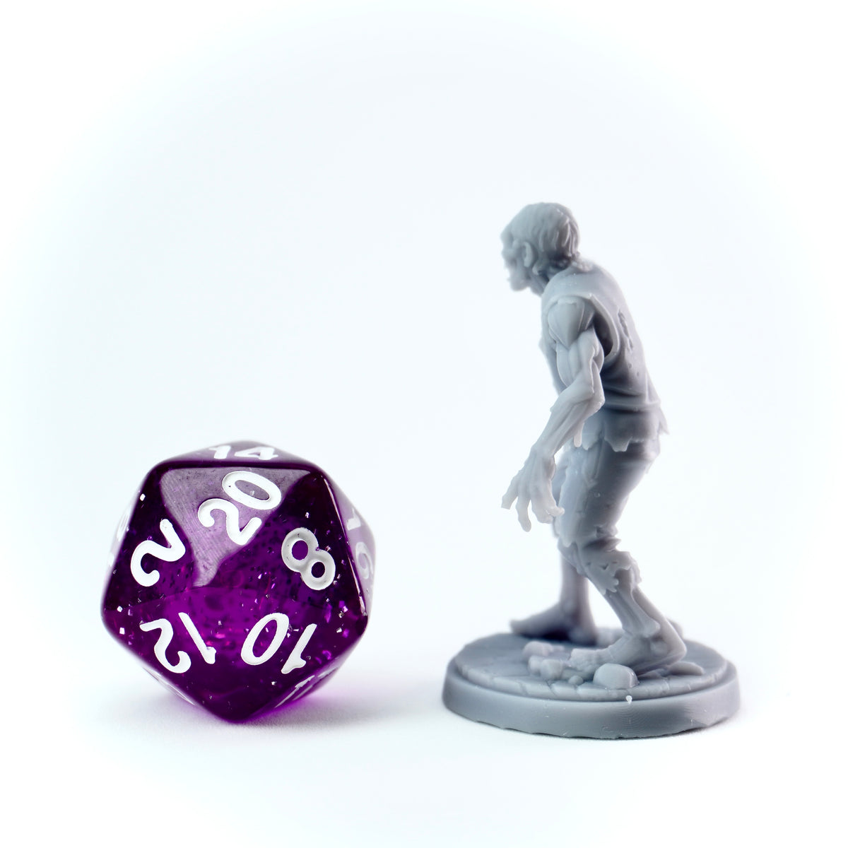 Gray zombie figurine next to a purple polyhedral dice on a white background