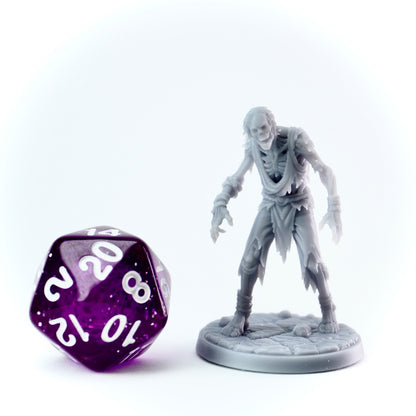 Gray zombie figurine next to a purple polyhedral dice on a white background