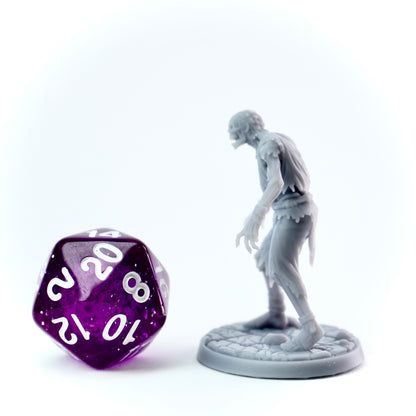 Gray zombie figurine next to a purple polyhedral dice on a white background