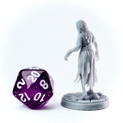 Gray figurine of a hooded figure next to a purple polyhedral dice on a white background