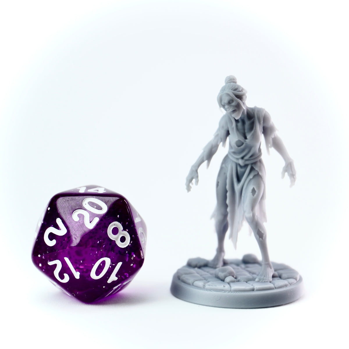 Gray miniature figure of a zombie-like creature next to a purple twenty-sided die on a white background