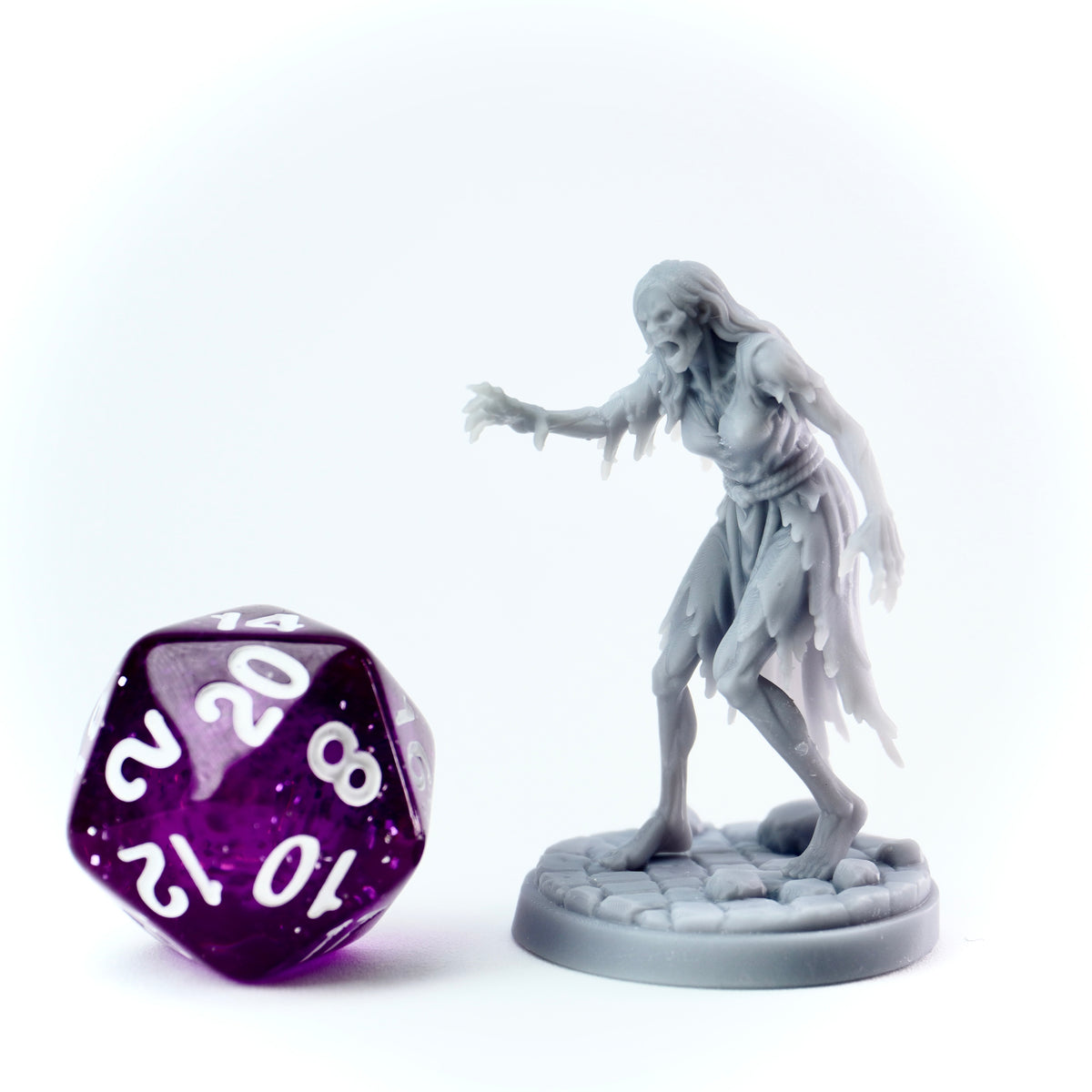 Gray miniature figure of a ghostly creature next to a purple polyhedral dice on a white background