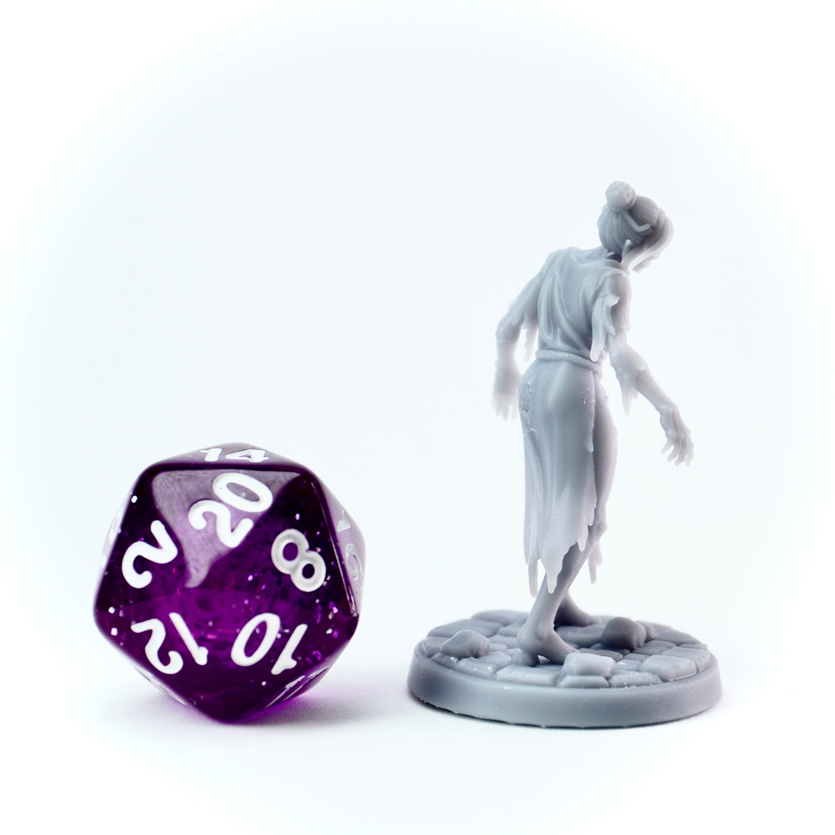 Gray figurine of a person standing on a pedestal next to a large purple polyhedral dice with white numbers.